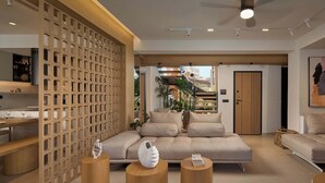 A modern living room with a sectional sofa, wooden coffee tables, and a decorative wall panel. - Ficus Seafront Villa, Eco Pool & Close to Beach (CQ6M+WCC Bali, Greece)