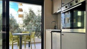 Une cuisine moderne équipée d’un four encastré, d’un évier et d’un coin repas avec des chaises et une table jaunes.