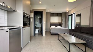 Une chambre d’hôtel moderne équipée d’une kitchenette, d’un lit, d’un canapé et d’une petite table.