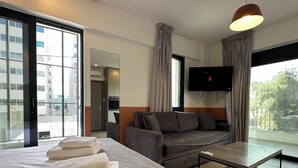 Une chambre d’hôtel moderne équipée d’un lit, d’un canapé, d’une télévision et d’un balcon avec vue.