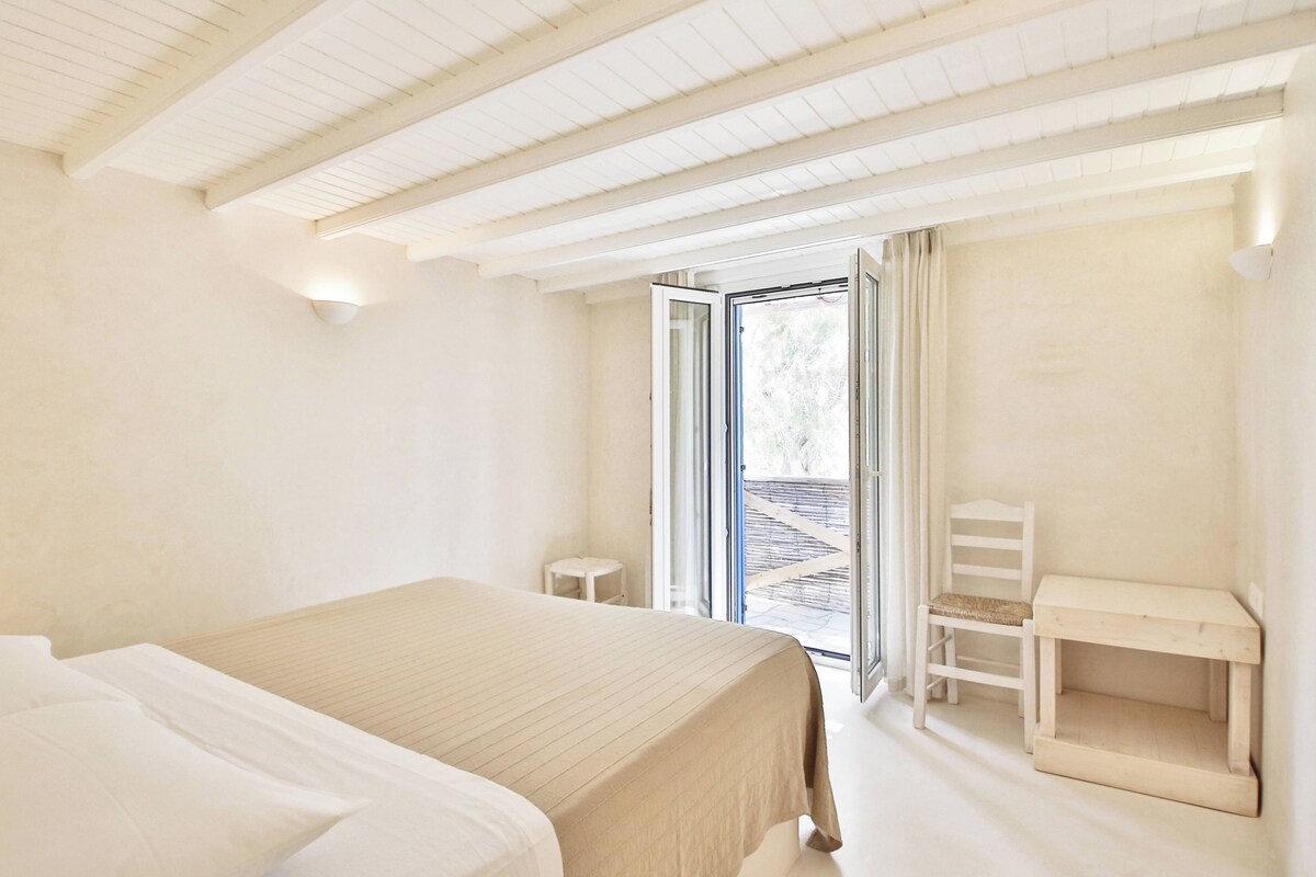 A bedroom with a bed, a desk, and a chair.