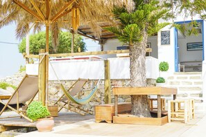 Un espacio de estar al aire libre con madera, que incluye una mesa, sillas y una hamaca.