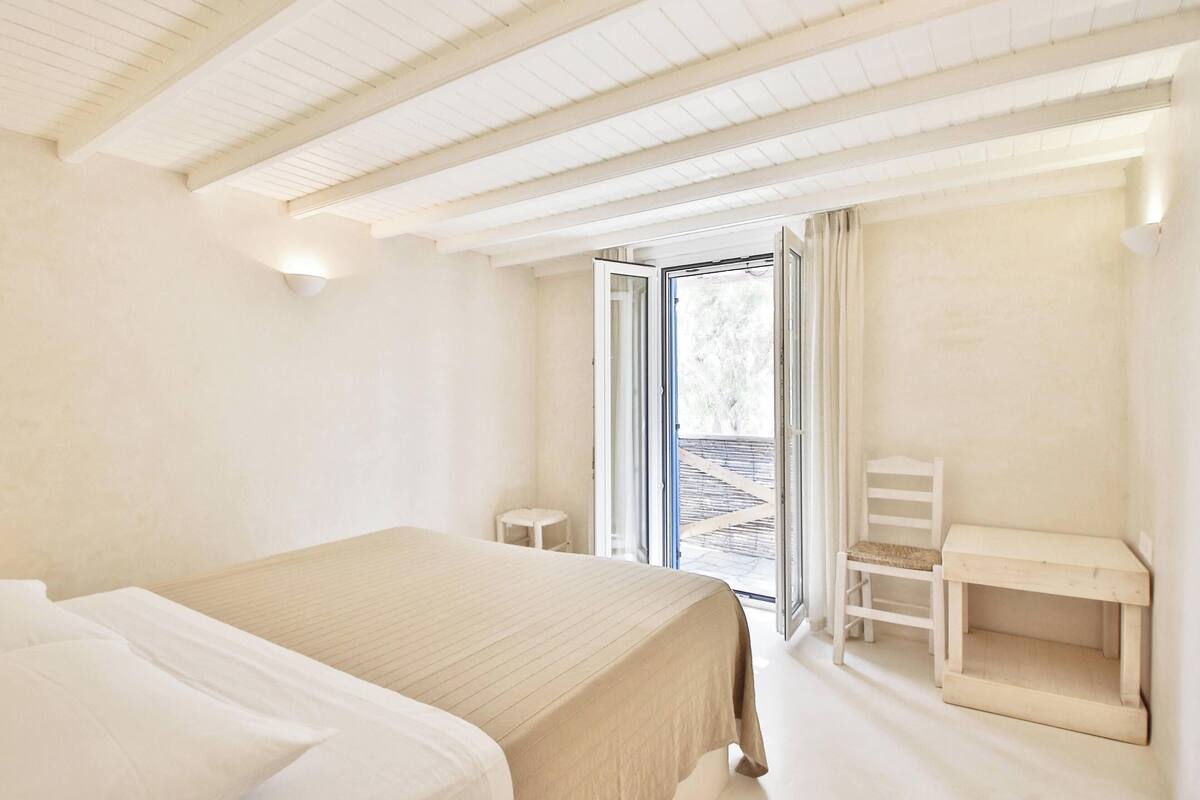 A bedroom with a bed, a desk, and a chair.
