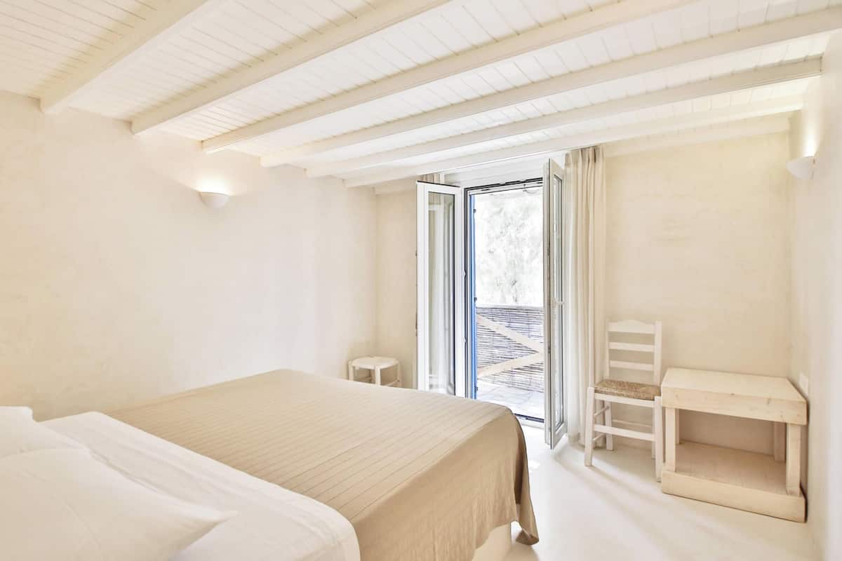 A bedroom with a bed, a desk, and a chair.