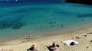 A beach with clear turquoise water, sandy shore, and rocky cliffs. - Baba Houlakia (Mykonos)