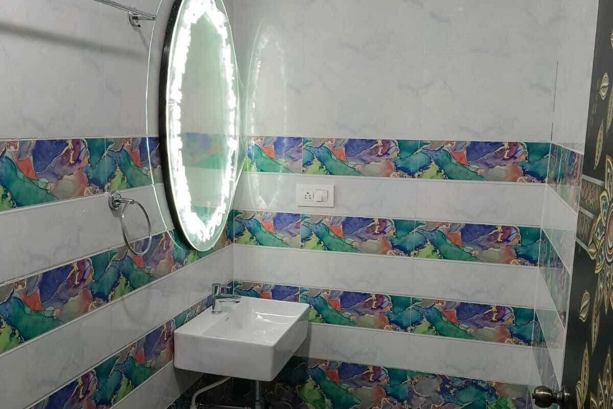 A bathroom with a white sink, a mirror, and colorful mosaic tiles on the walls and floor.