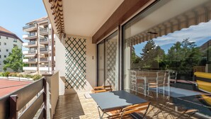 Un balcón con una mesa y sillas, un vidrio que da a un patio, y un suelo con diseño.
