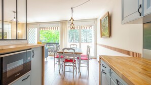 Una cocina con encimera de madera, una mesa de comedor con sillas y vistas a zonas verdes.