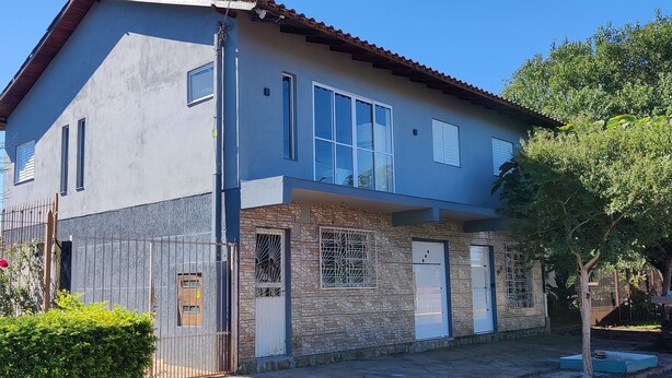 A two-story house with a stone facade, large windows, and a metal gate.
