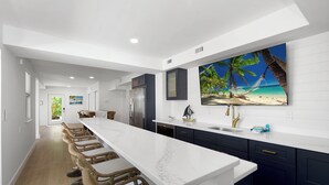 Een moderne keuken met een groot kookeiland, donkere kasten en wanddecoratie met een strandthema.