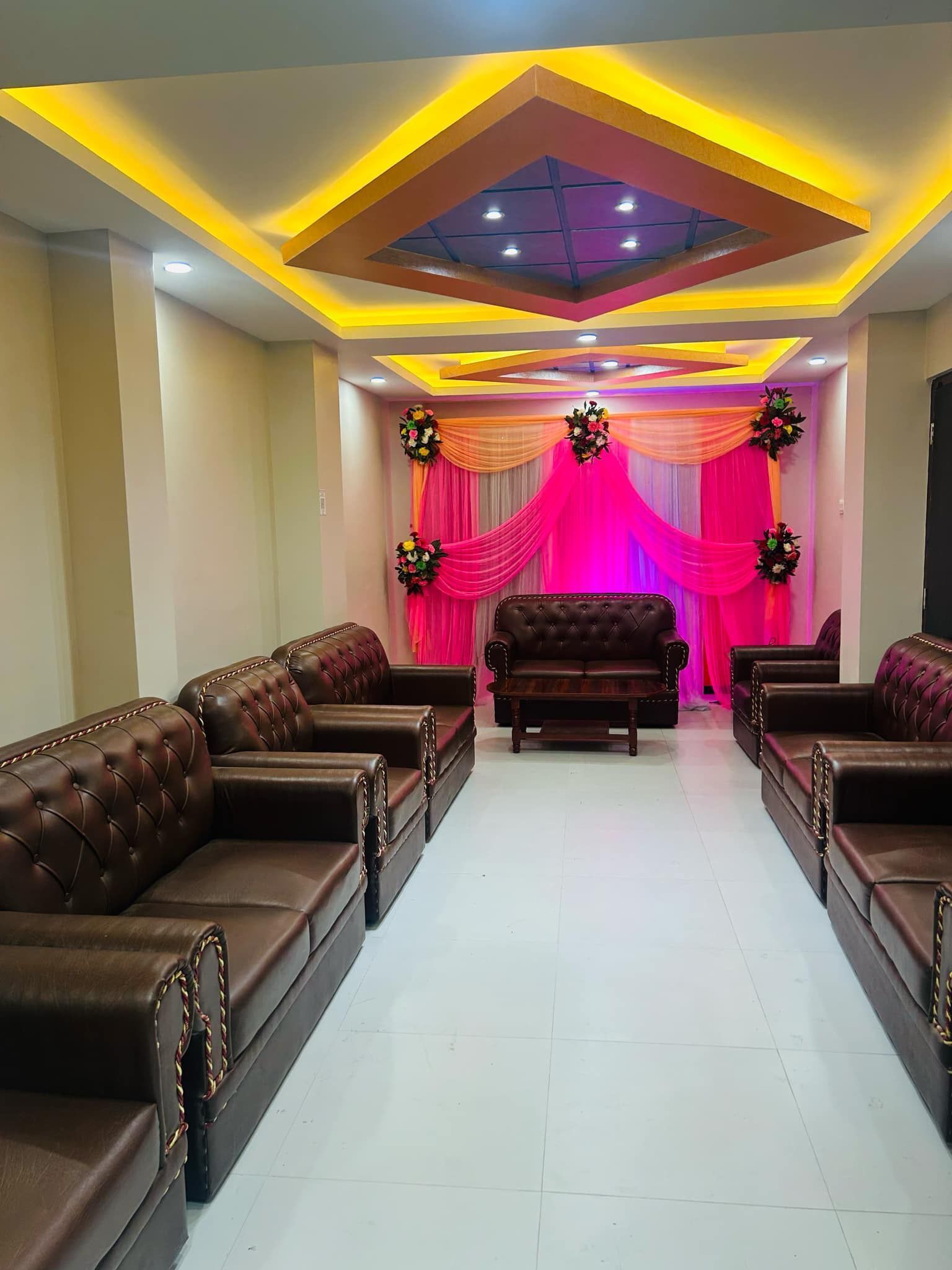 A room with leather sofas arranged in a row, a central sofa, and a ceiling with recessed lighting.