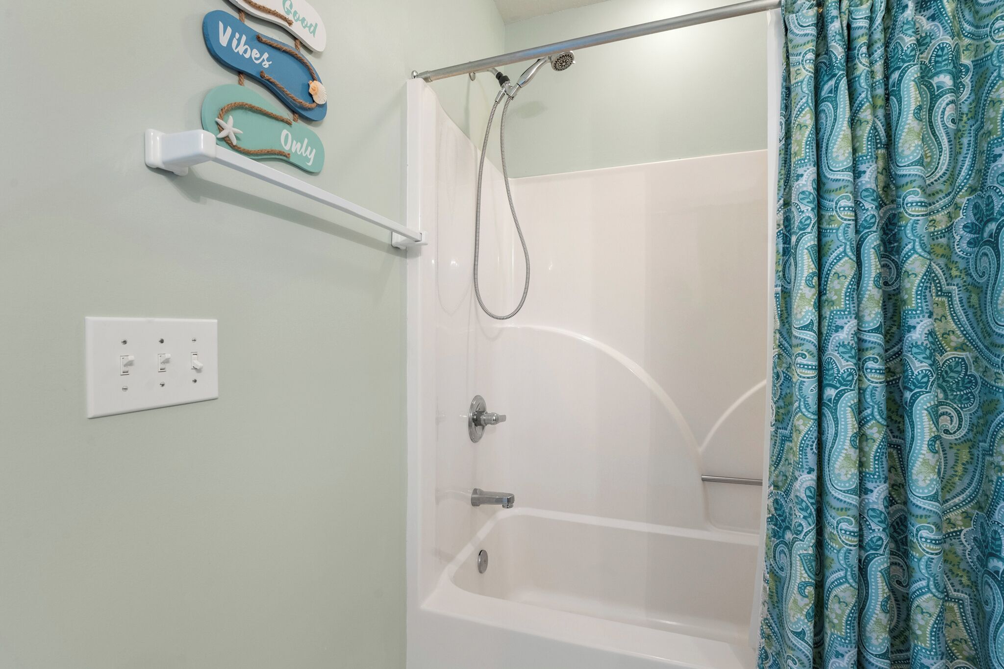 A shower area with a showerhead, a towel rack with decorative towels, and a shower curtain.