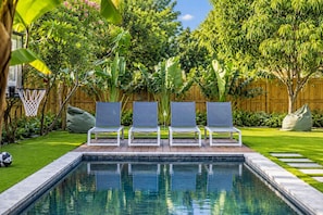 Une piscine avec trois chaises longues et une terrasse en bois.