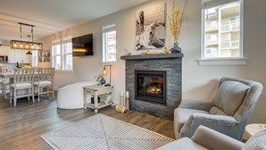 Una sala de estar moderna con chimenea, un comedor y vistas a un balcón.