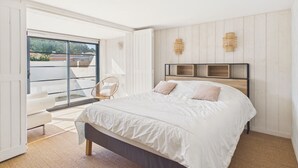 Un dormitorio con cama, una silla, una ventana y una puerta.