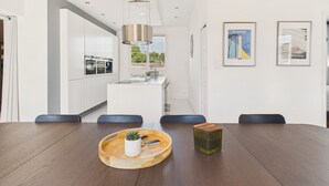 Una cocina moderna con armarios blancos, una isla central e iluminación colgante.