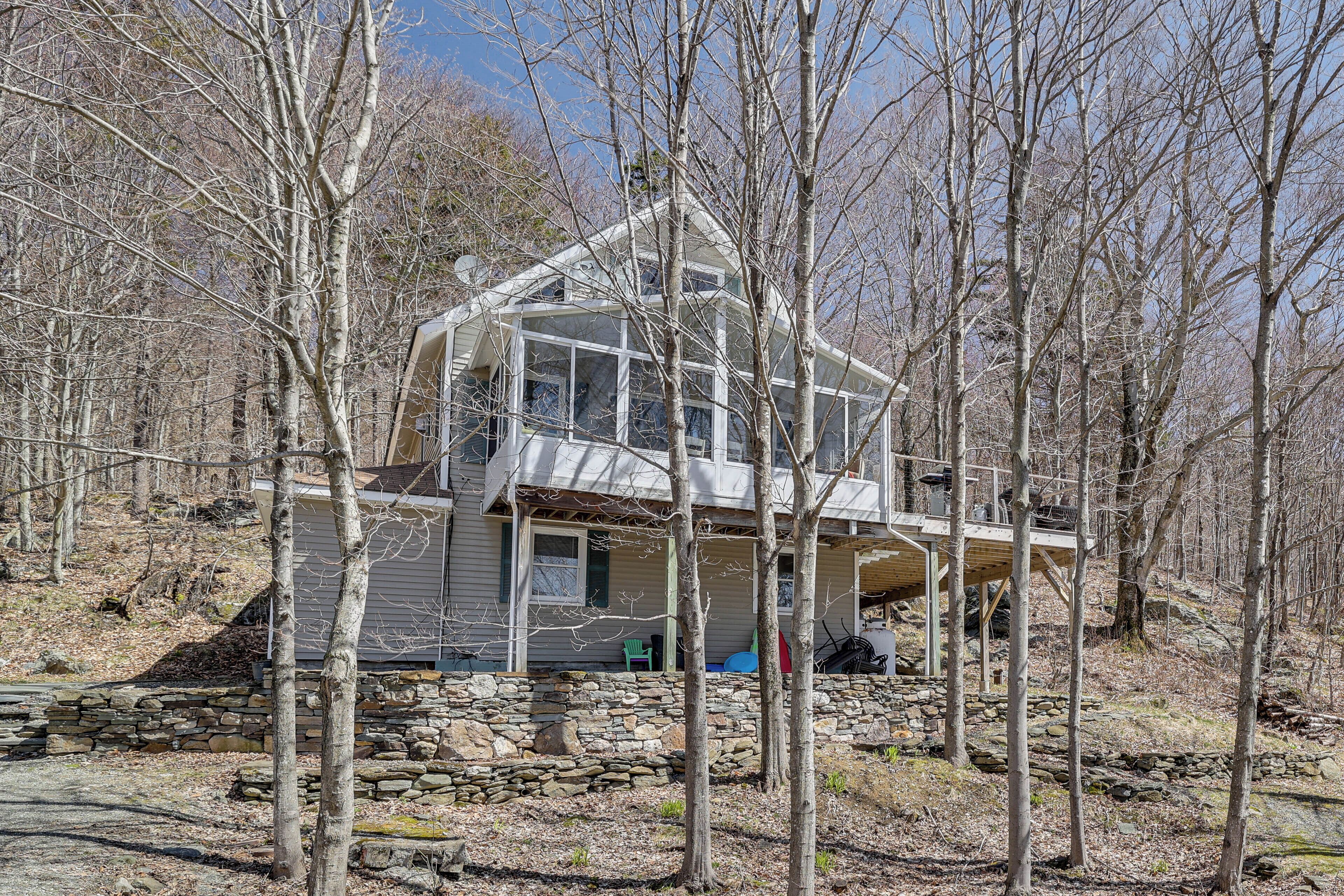 Une grande maison à deux étages, avec des fondations en pierre et une véranda en verre.