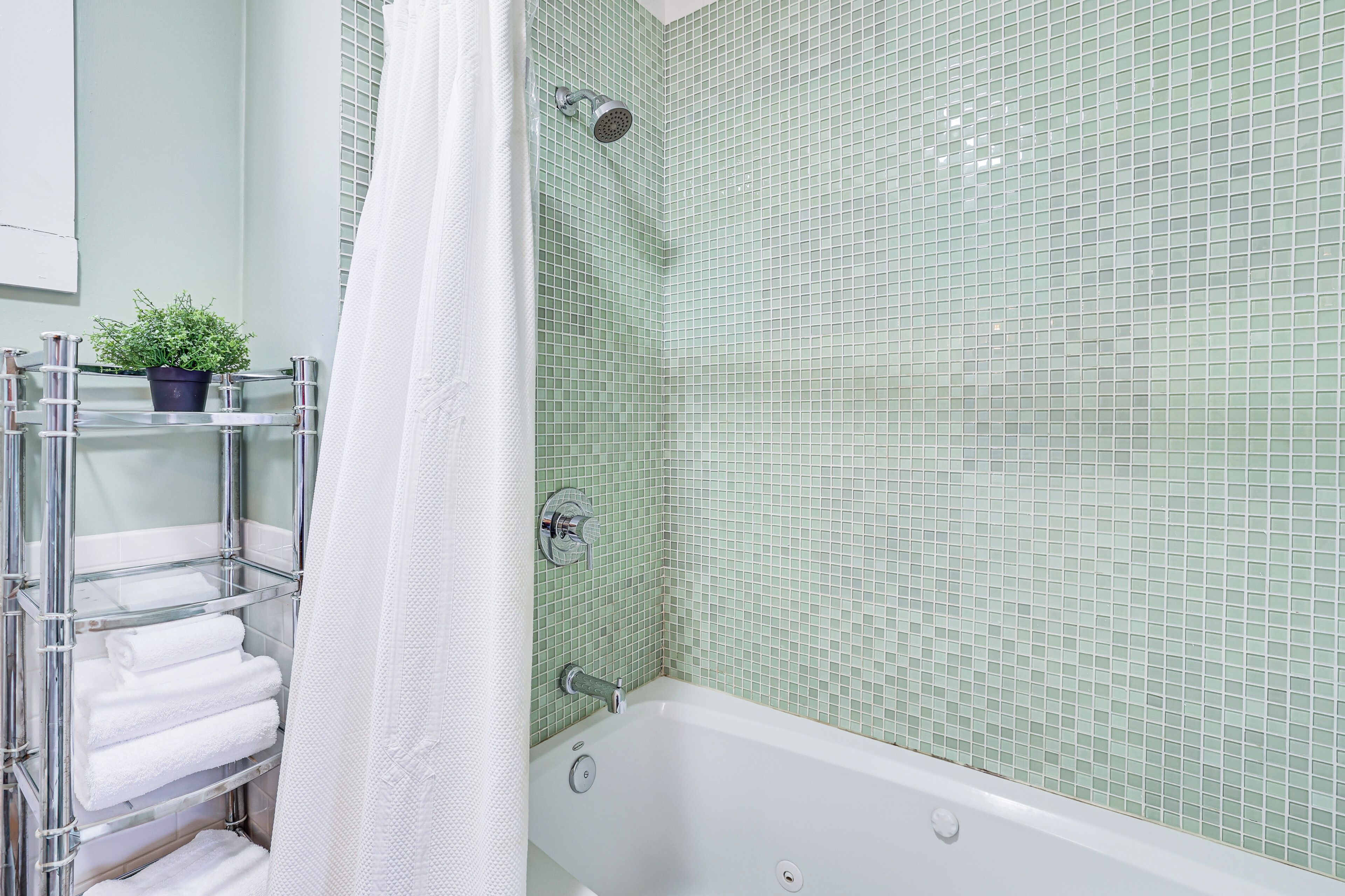 A bathroom with a bathtub, a shower, and a shelf with towels.