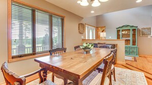 A dining area with a wooden table and chairs, a green cabinet, and a window with blinds. - Family-friendly Ozarks Getaway < 21 Mi to Branson! (Omaha)