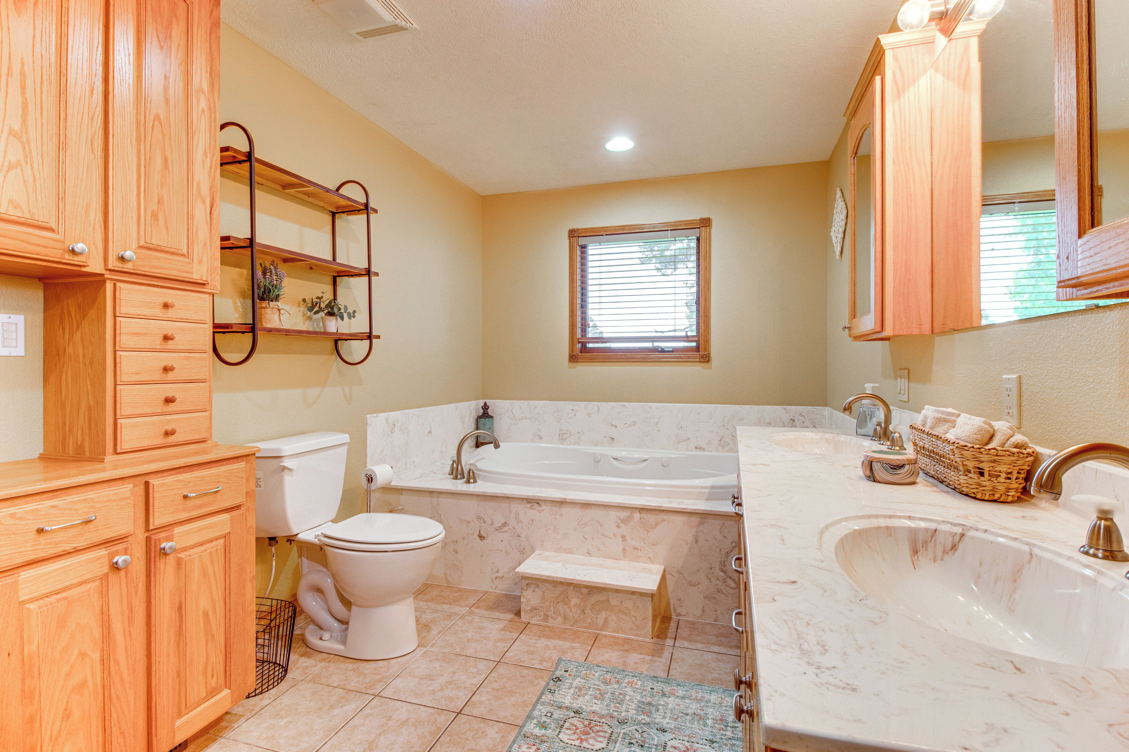 Un baño con armarios de madera, inodoro, bañera y lavamanos.