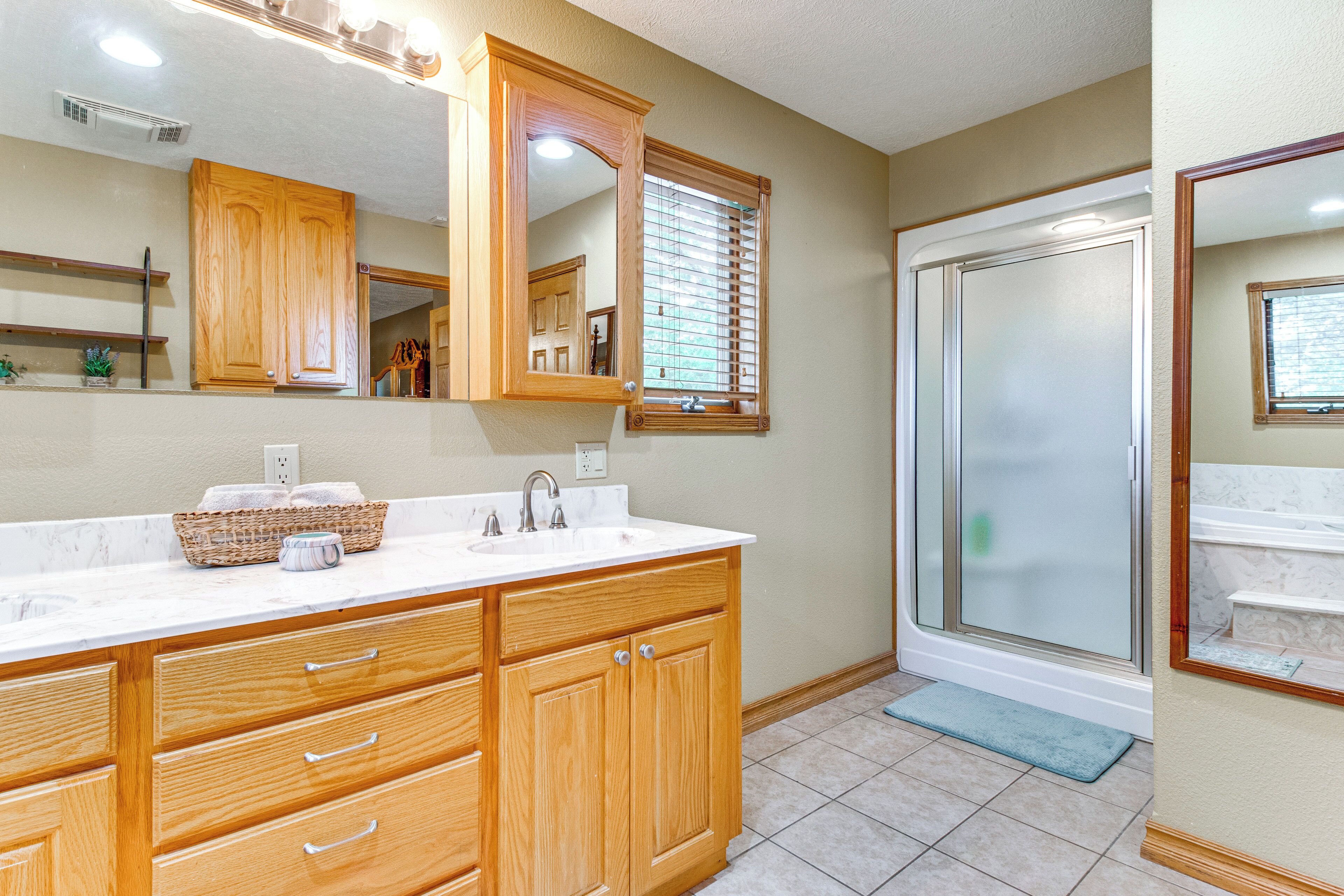 A bathroom with wooden cabinets, a white sink, and a shower with a glass door.