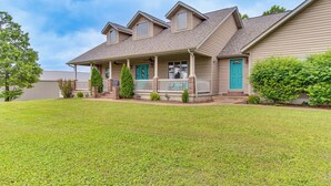 A two-story house with a covered porch, a front yard, and a small tree. - Family-friendly Ozarks Getaway < 21 Mi to Branson! (Omaha)