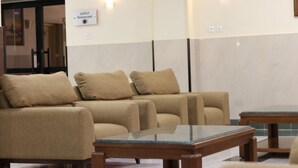 Un área de estar con tres sofás beige y una mesa de vidrio.