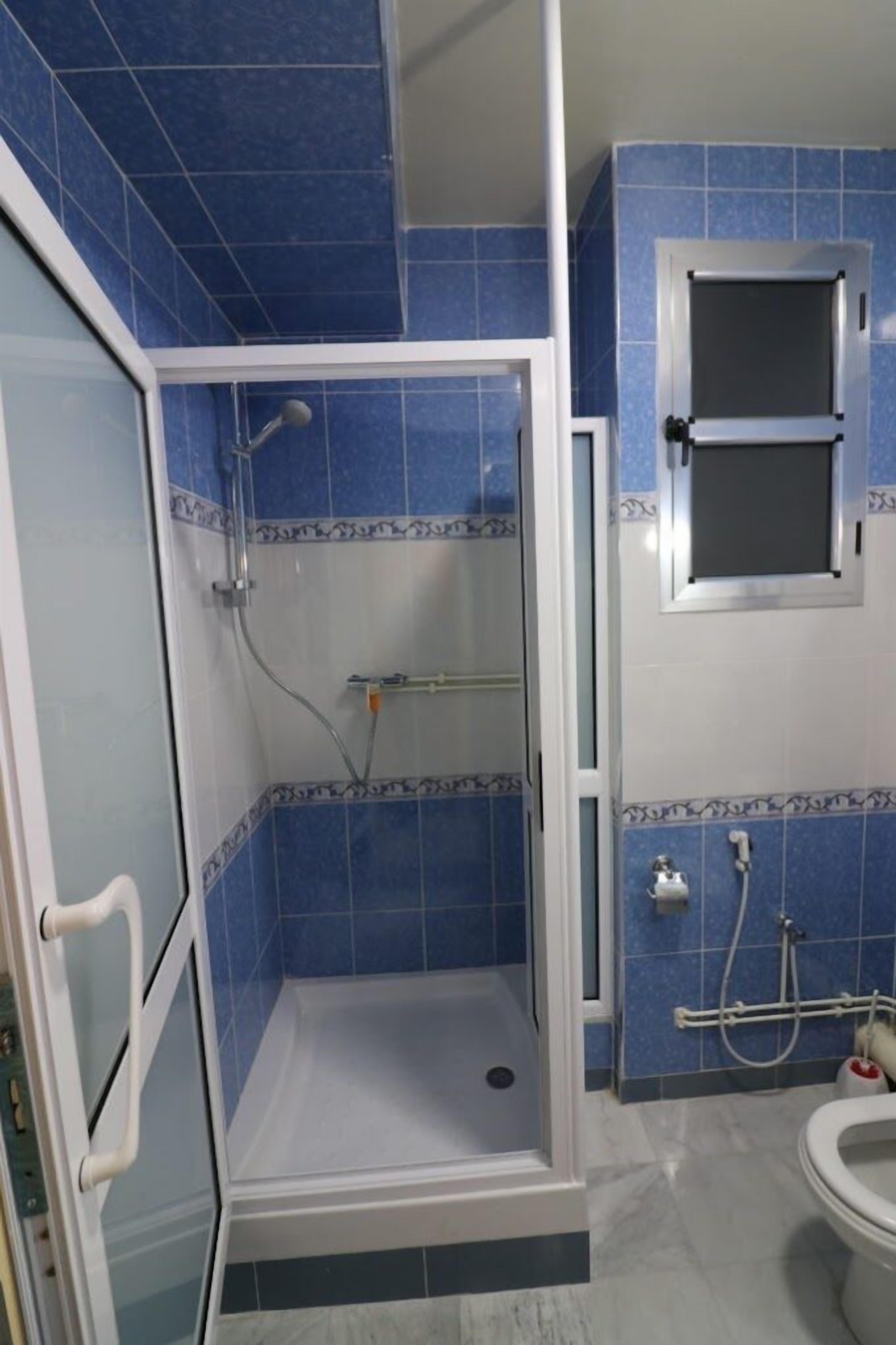 A bathroom with a shower enclosure, a toilet, and a window.