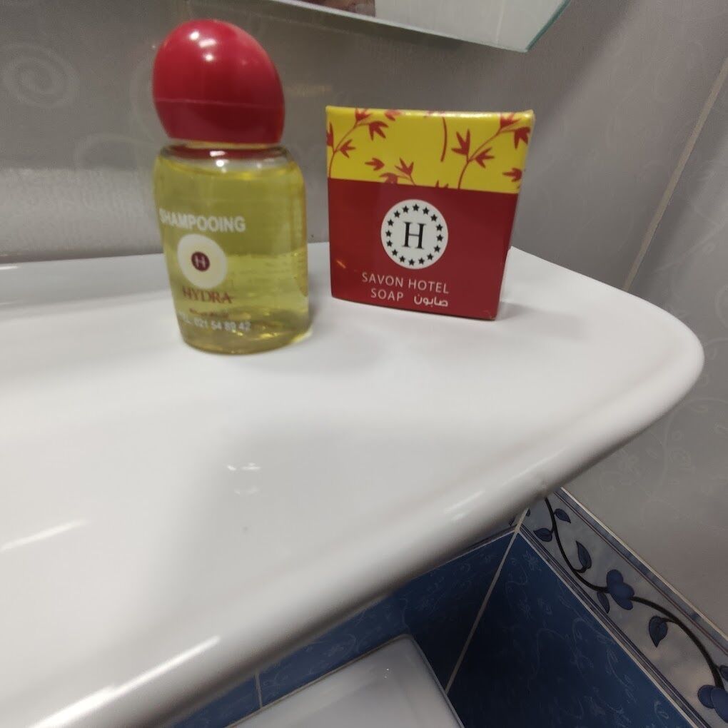 Un baño con un lavamanos blanco, una botella de champú y una pastilla de jabón.