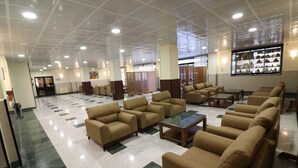 Un vestíbulo amplio con varios sofás y una mesa de centro, una zona de recepción y una exhibición de objetos en la pared.