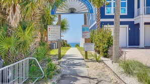 Un sendero que lleva a una playa con palmeras y un edificio azul.