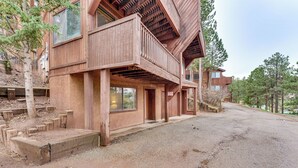 Een houten chalet met een balkon, een grindpad en een bebost achtergrond.