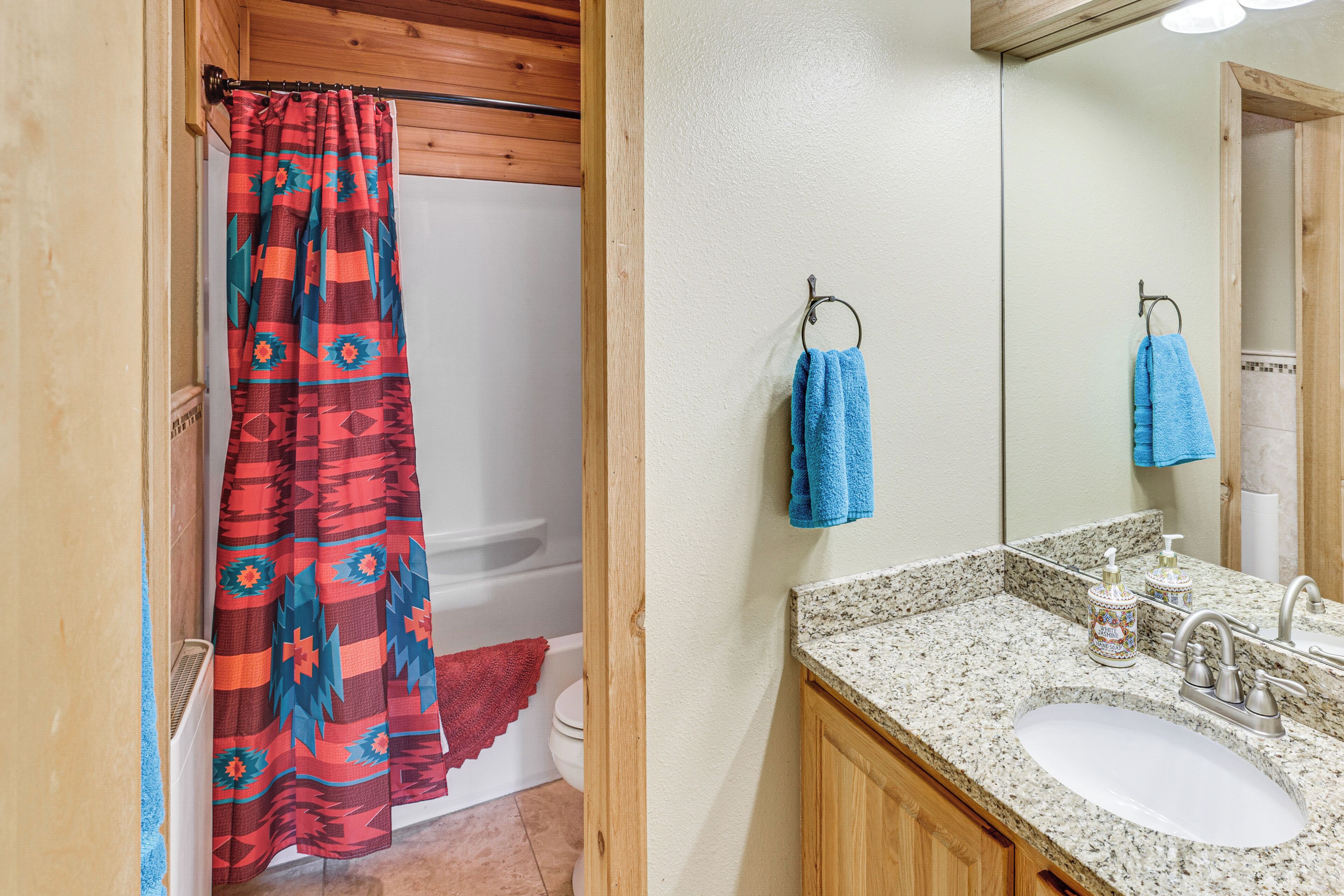 A bathroom with a shower curtain, a sink, and a mirror.