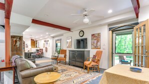 A spacious living room with a leather sofa, a wooden coffee table, and a TV mounted on the wall. - Jasper Apartment w/ Patio & Creek Access (Jasper)