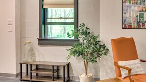 A room with a window, a potted plant, a chair, a small table, and a shelf unit. - Jasper Apartment w/ Patio & Creek Access (Jasper)