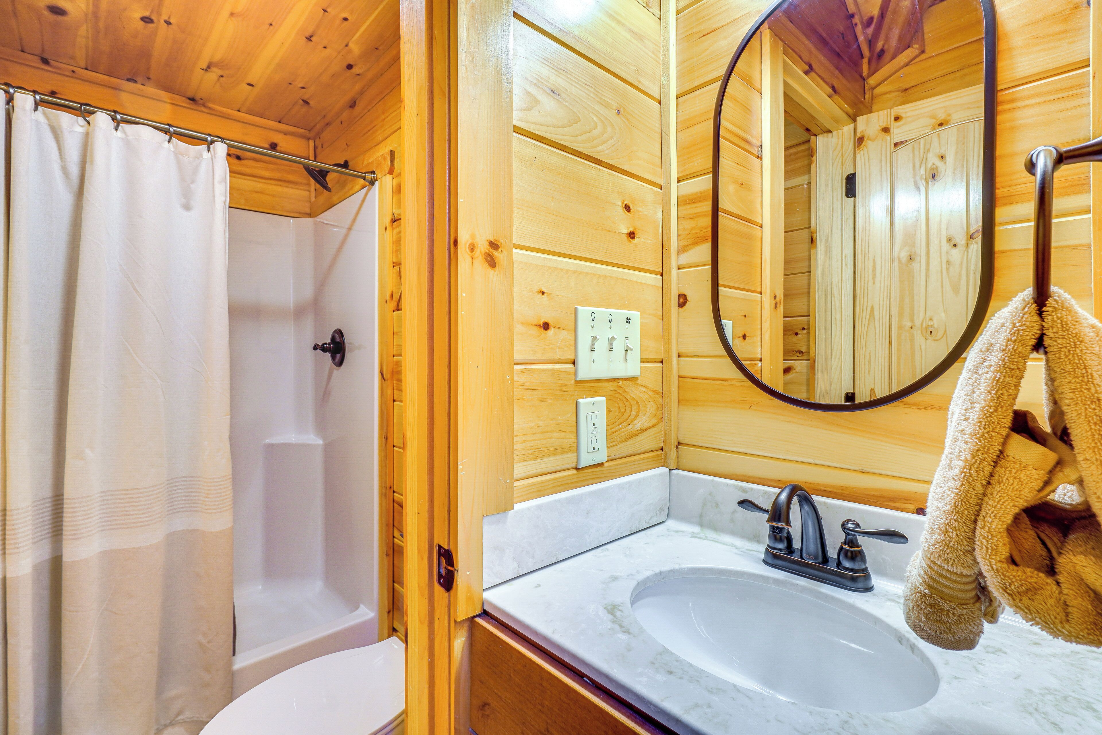 A wooden cabin bathroom with a white sink, a mirror, and a shower curtain.
