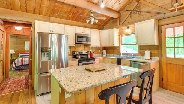 A wooden cabin interior with a kitchen featuring a refrigerator, microwave, stove, and wooden cabinets. - Updated Mtn Cabin on 20 Acres w/ Large Waterfall (Jasper)