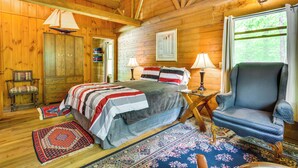 A wooden cabin bedroom with a bed, two lamps, a chair, and a window. - Updated Mtn Cabin on 20 Acres w/ Large Waterfall (Jasper)