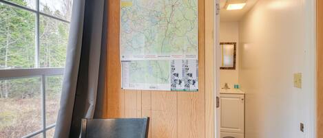 A room with a large window, a map on the wall, a chair, and a door leading to a bathroom.
