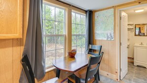 Un comedor con una mesa y sillas de madera, una ventana con cortinas y un mapa en la pared.