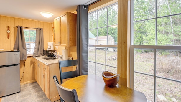 Una cocina compacta con armarios de madera, un refrigerador, un lavamanos y una ventana con cortinas.