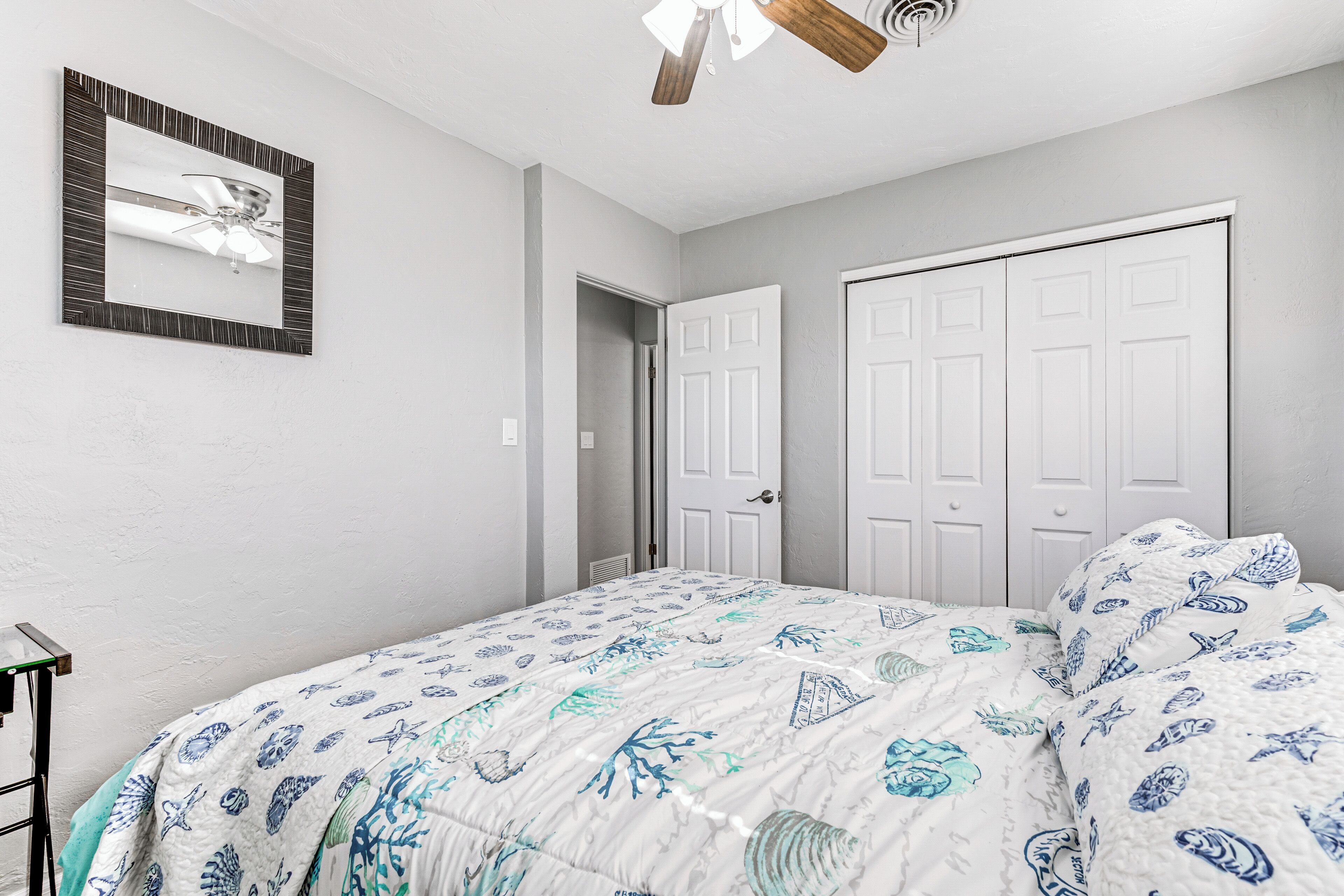 Une chambre à coucher avec un lit, un ventilateur de plafond et deux portes blanches.