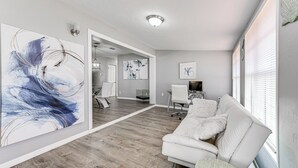 Una sala de estar moderna con un sofá blanco, un cuadro abstracto grande y un suelo de madera.