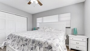 Un dormitorio con cama, mesita de noche, cómoda y ventilador de techo.