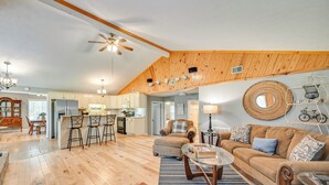 A spacious living area with a wooden ceiling, a kitchen in the background, and a cozy seating area with a sofa and chairs. - Access to Rough River Lake! Family Home w/ Deck (Leitchfield)