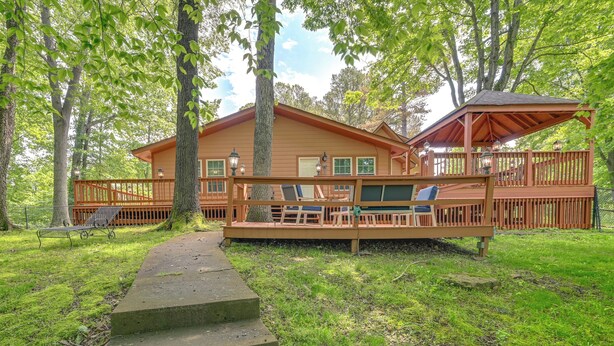 A wooden cabin with a deck, outdoor seating, and a covered area. - Access to Rough River Lake! Family Home w/ Deck (Leitchfield)