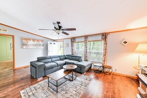 A living room with a sectional sofa, a coffee table, a ceiling fan, and a large window with curtains. - Kuttawa Vacation Rental w/ Smart TV, Near Marinas! (Kuttawa)