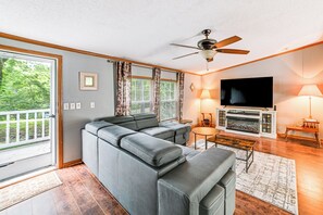 Una sala de estar moderna con un sofá modular, una chimenea, un televisor y un ventilador de techo.