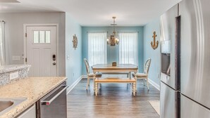 Una cucina moderna con lavastoviglie integrata, frigorifero in acciaio inossidabile e zona pranzo con tavolo e sedie in legno.