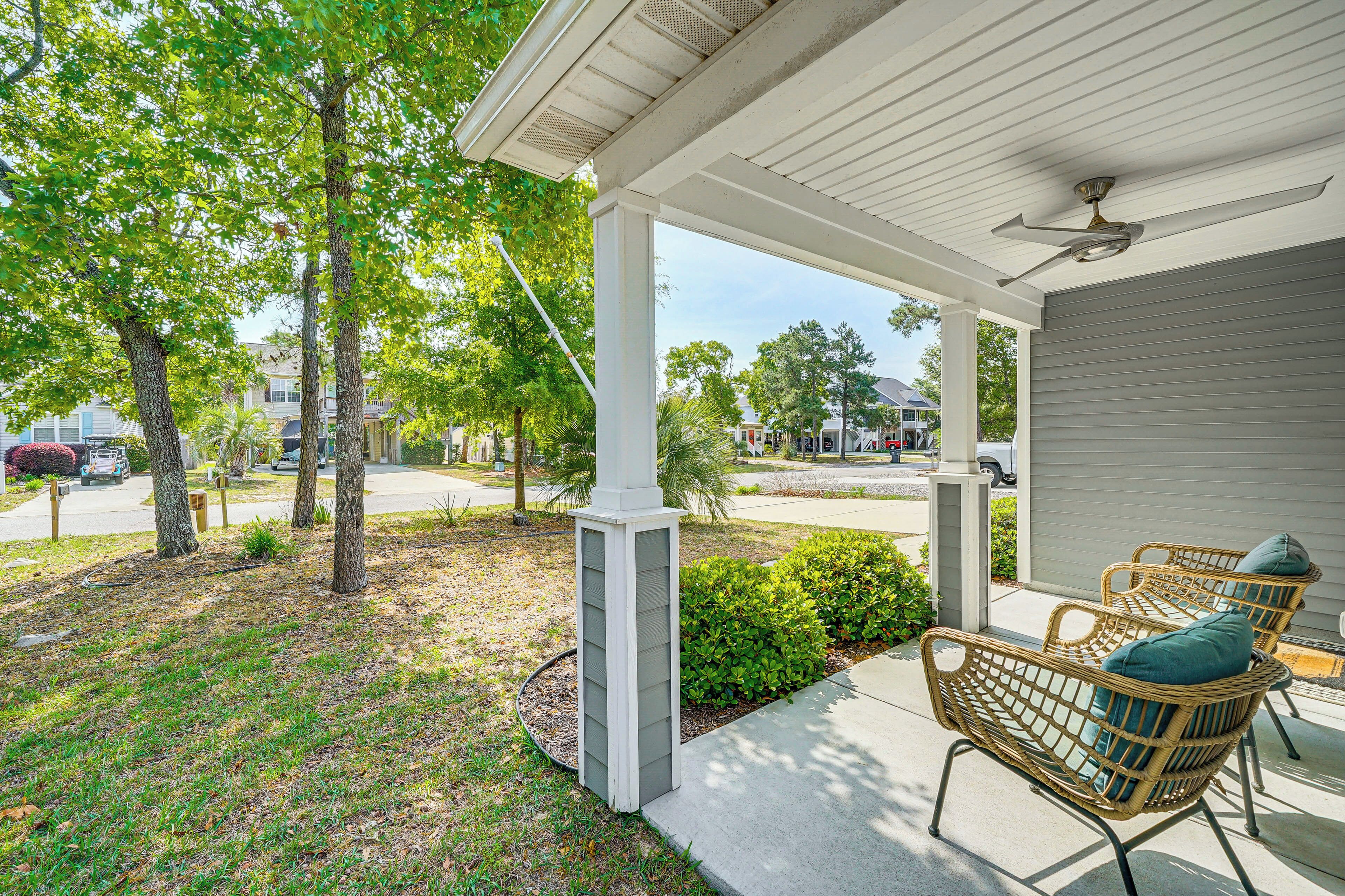 A covered porch with wicker chairs and a ceiling fan.
